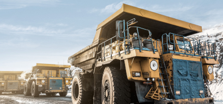 Three large yellow dump trucks lined up.