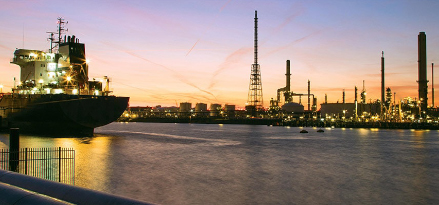 A sea freight vehicle in a panoramic cityscape at dusk with the ExxonMobil Rotterdam refinery in the background.