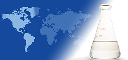 A laboratory flask with EHC 45/65 base stock on the foreground of a two-tone global map highlighting North and South America.