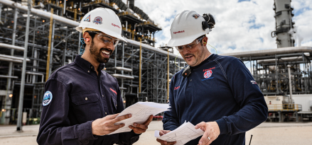 An ExxonMobil engineer points at refinery while on a phone call