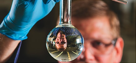 Scientist looking at clear liquid in a flask