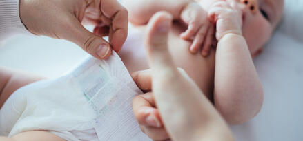 Picture of a baby getting a diaper put on.